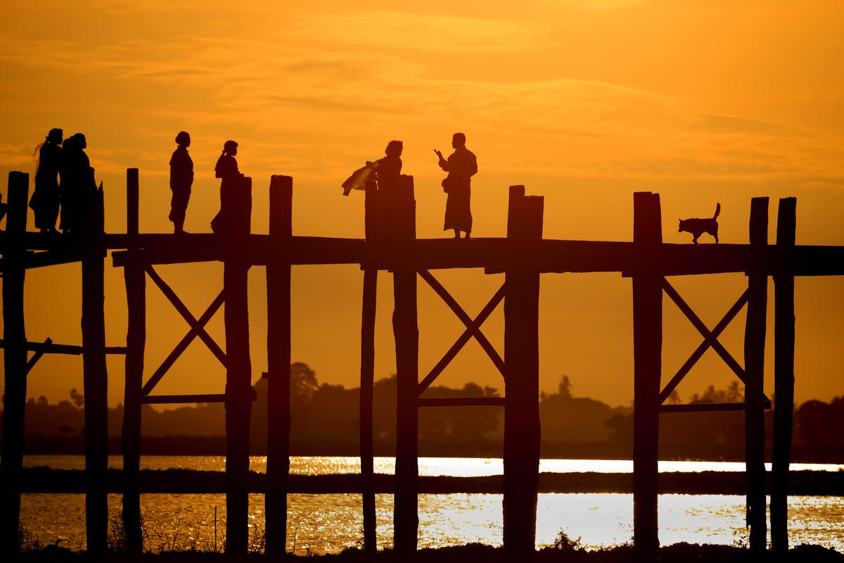 Silhouette of People and a Dog Walking on a Bridge