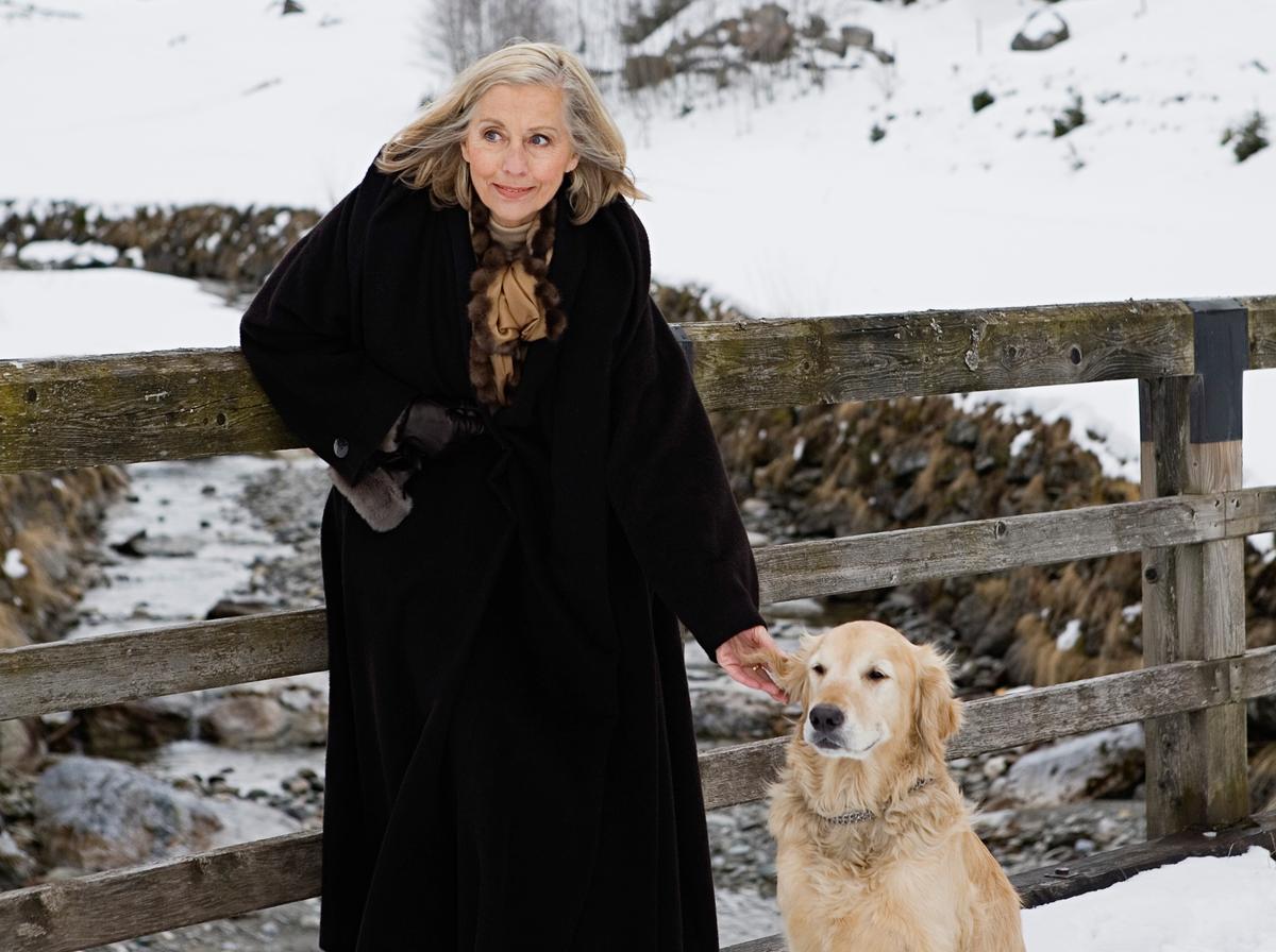 Active senior woman petting her dog in the snow in Austria