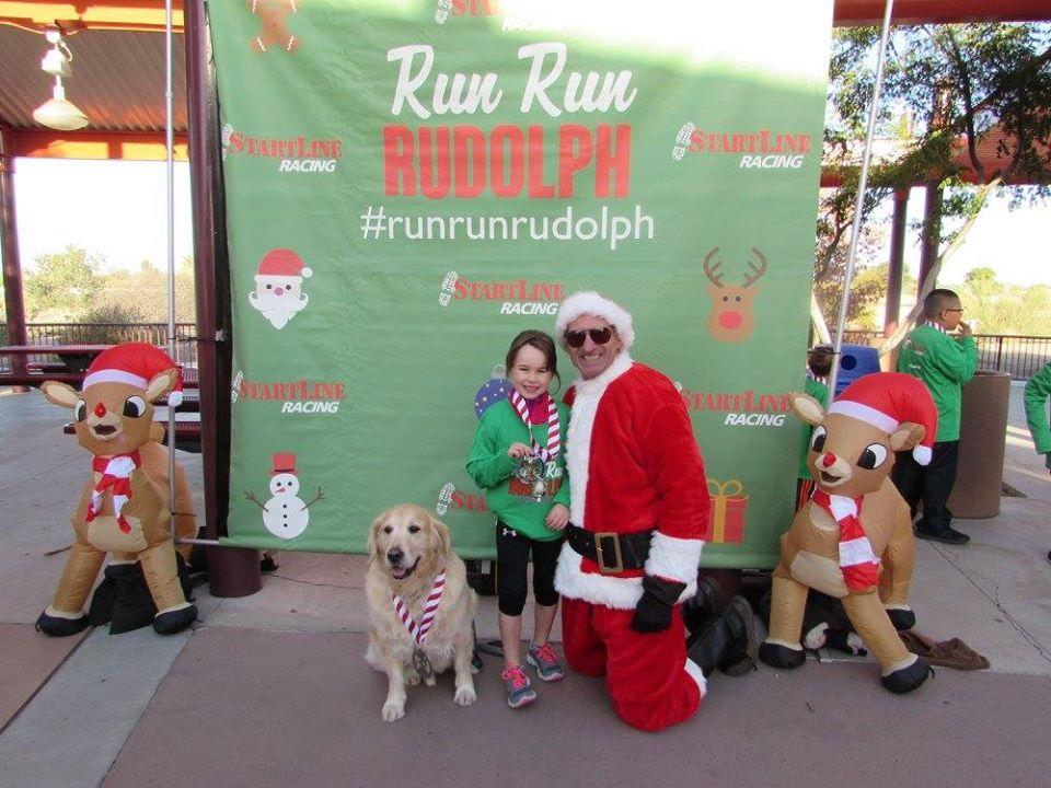A Man Dressed as Santa Poses With a Girl and a Dog at a Pet-Friendly Christmas Race in Arizona.