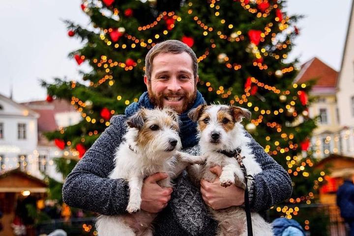 A Man and Two Jack Russel Terriers Pose at a Pet-Friendly Christmas Market.