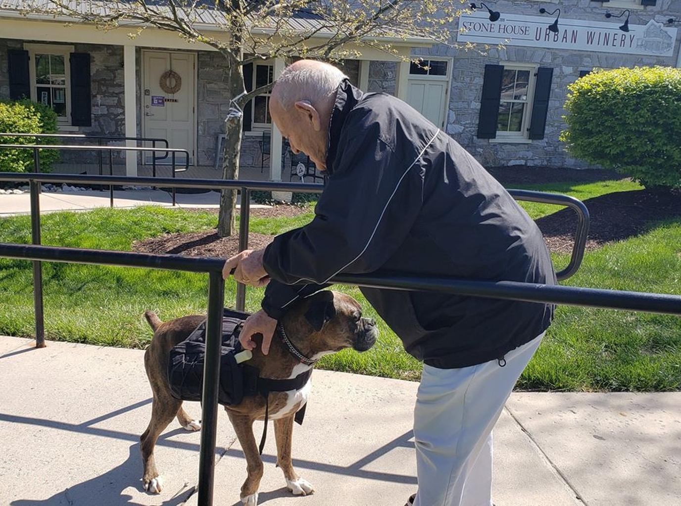 A Senior Citizen Pets Soda Pup the Wine Delivery Dog.