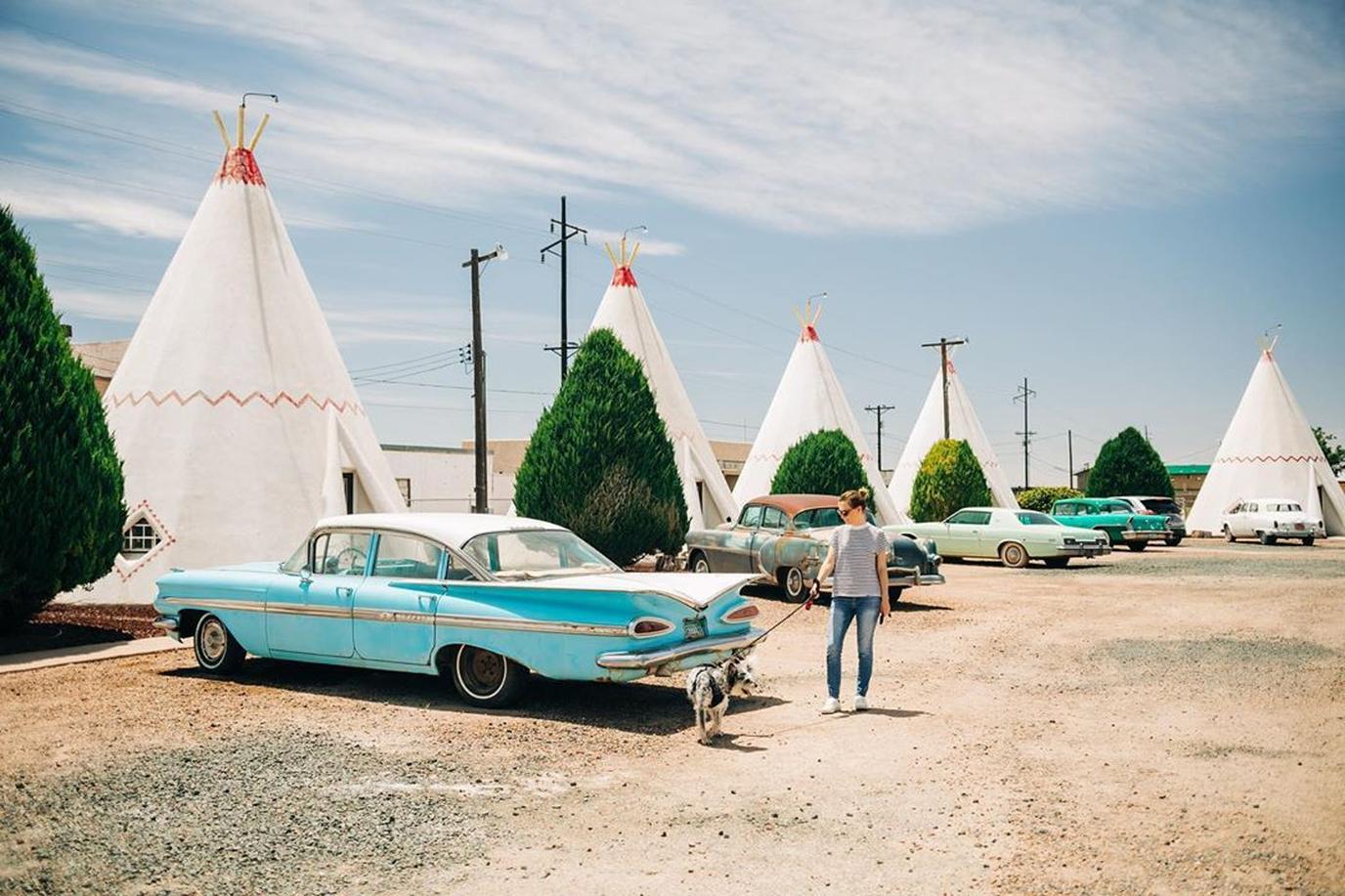 Woman and Dog Look at a Retro Car at the Pet-Friendly Wigwam Motel.