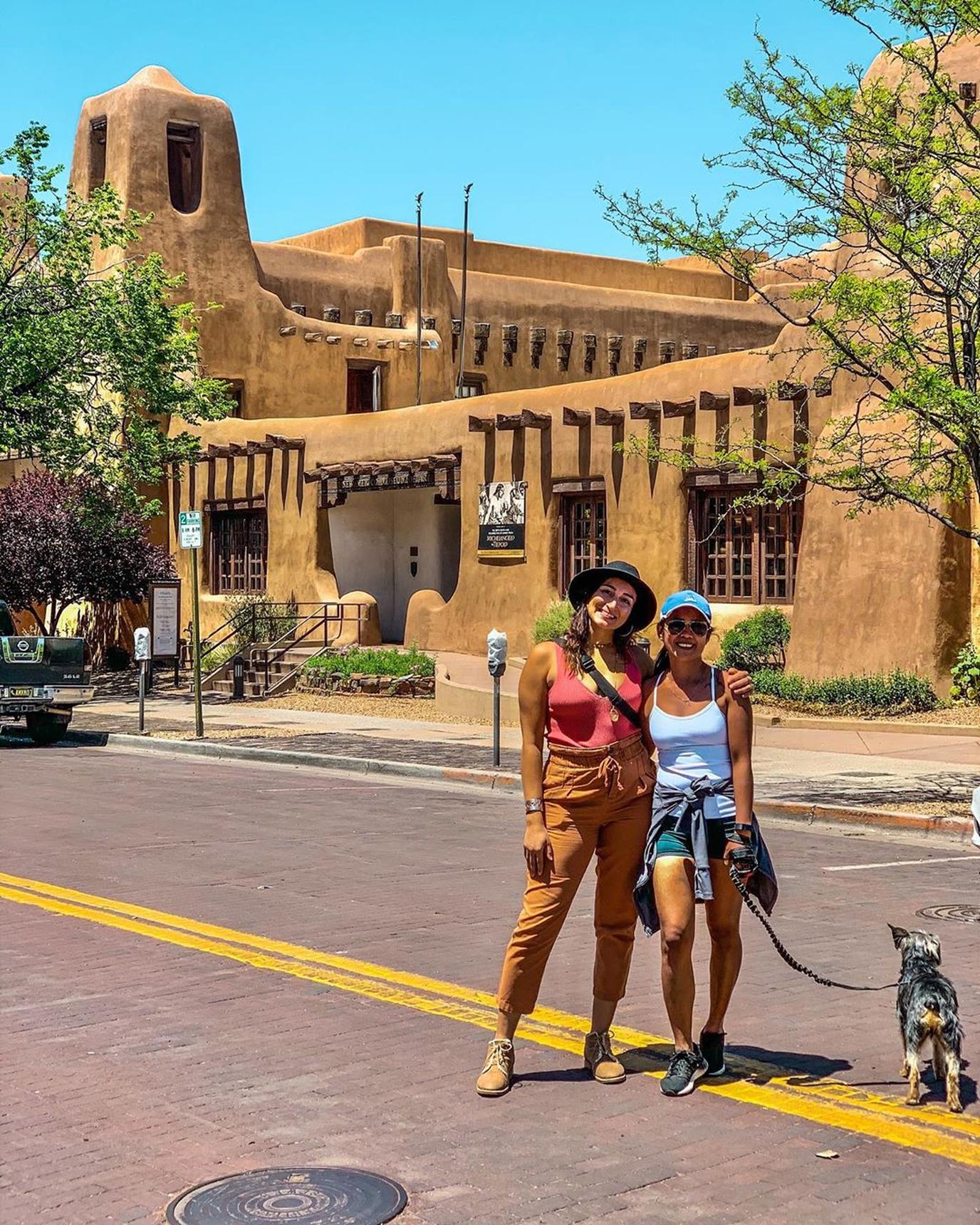 Two Woman and a Dog Pose for a Photo in the Middle of a Street in Pet-Friendly Santa Fe.