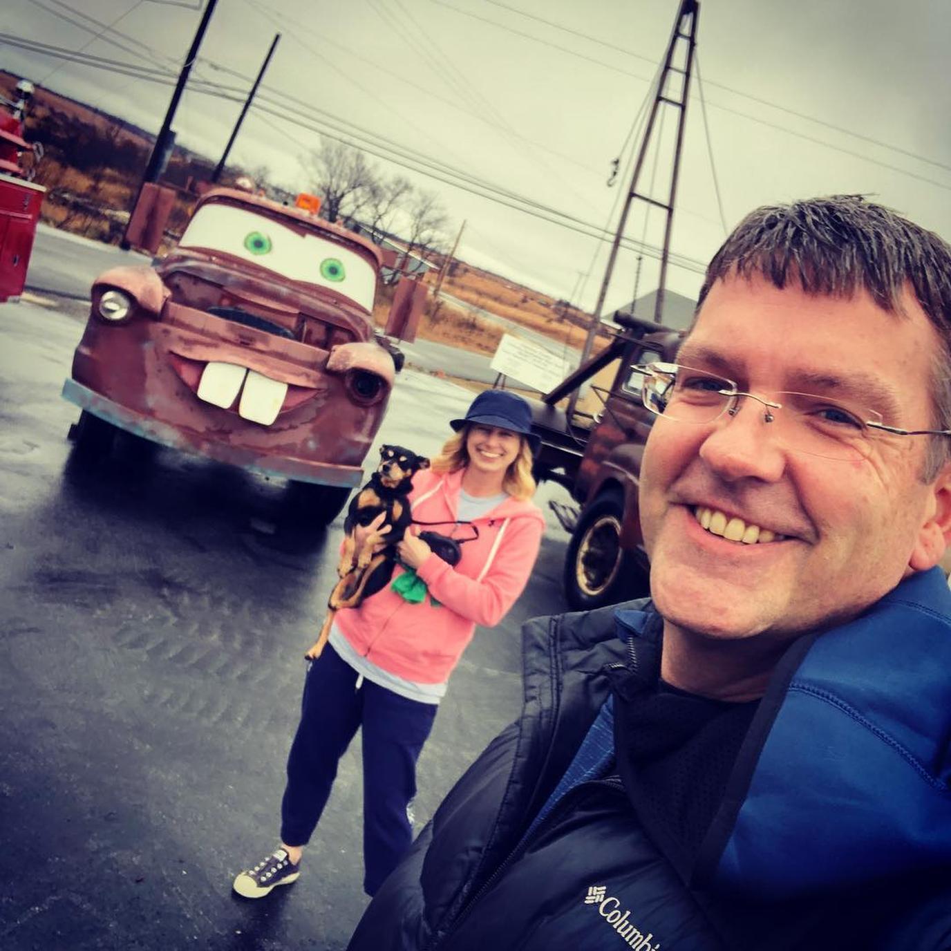 A couple and their dog pose next to Cars On the Route in Kansas.