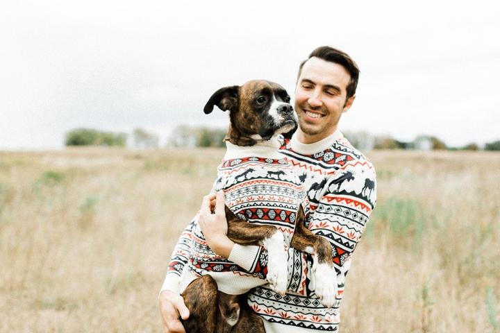 A man and his dog wear matching Christmas sweaters.