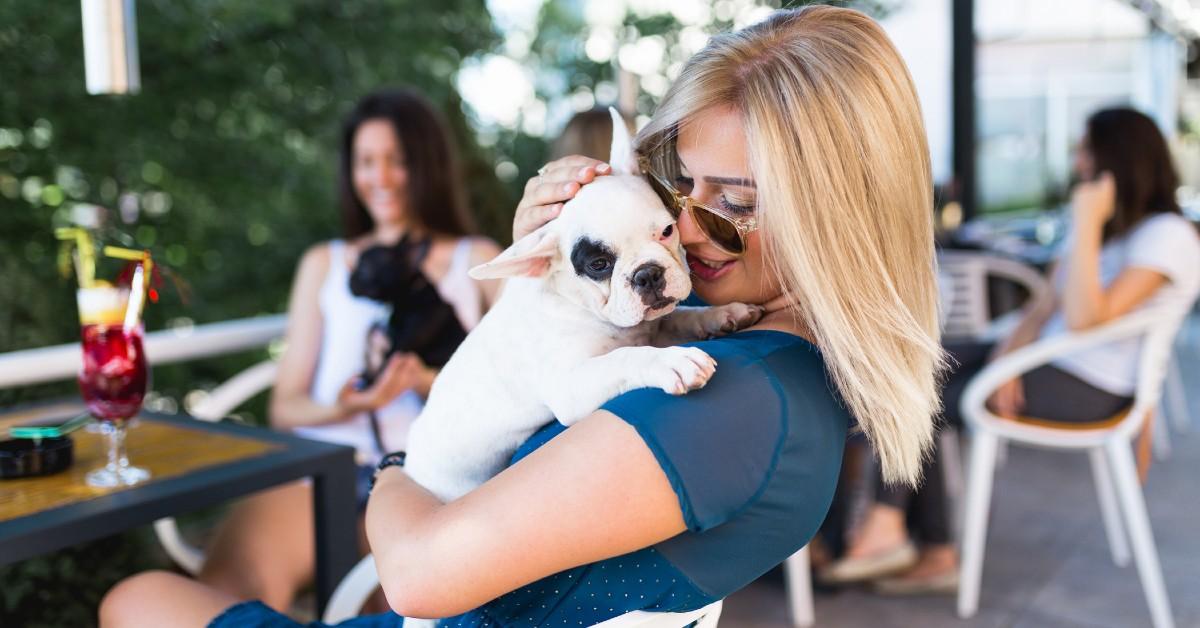 A woman with her dog at Happy Hour at a pet-friendly restaurant.