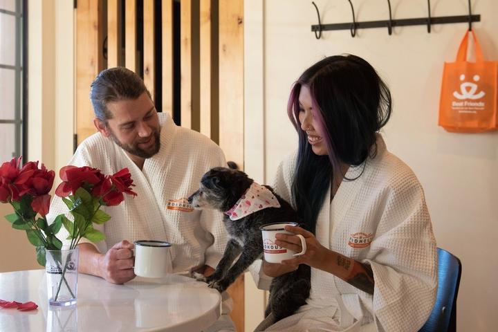 A couple enjoys coffee with their dog.