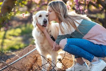 Pamper Dog Moms This Mother's Day A Woman kisses a Golden Retriever.