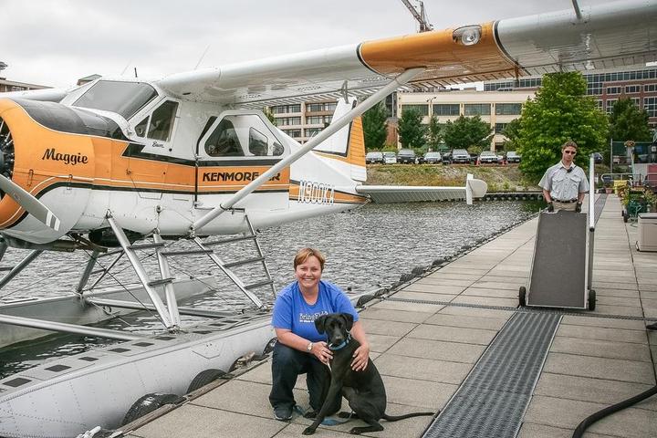 Woman and a dog in front of a sea plane.