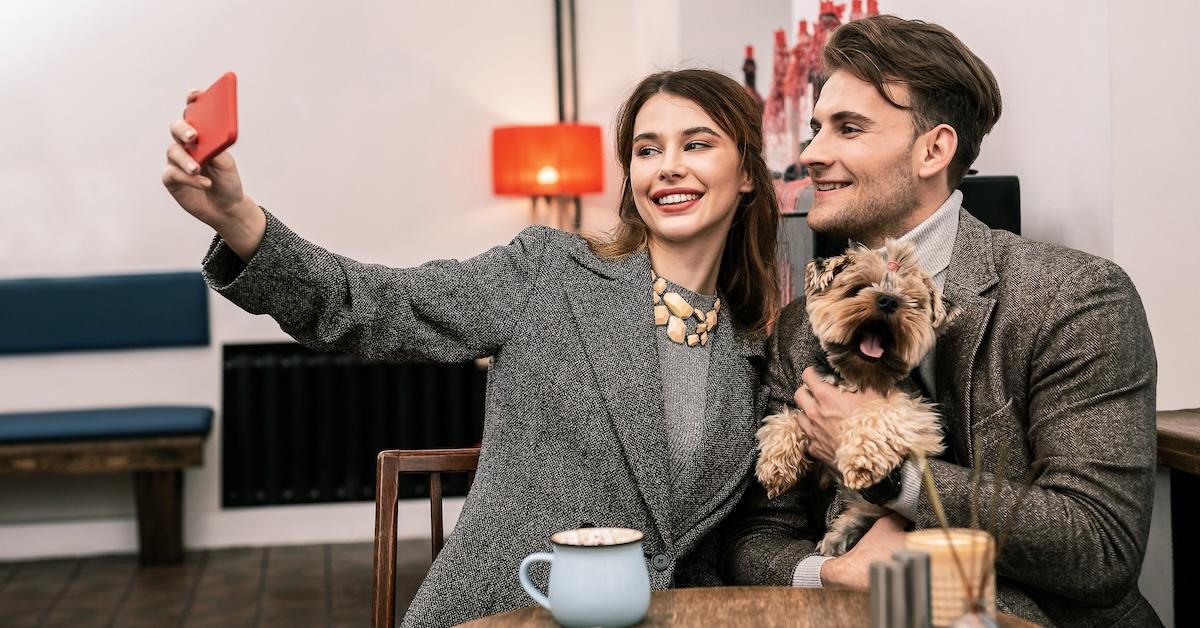 A couple and a dog take a selfie at dinner