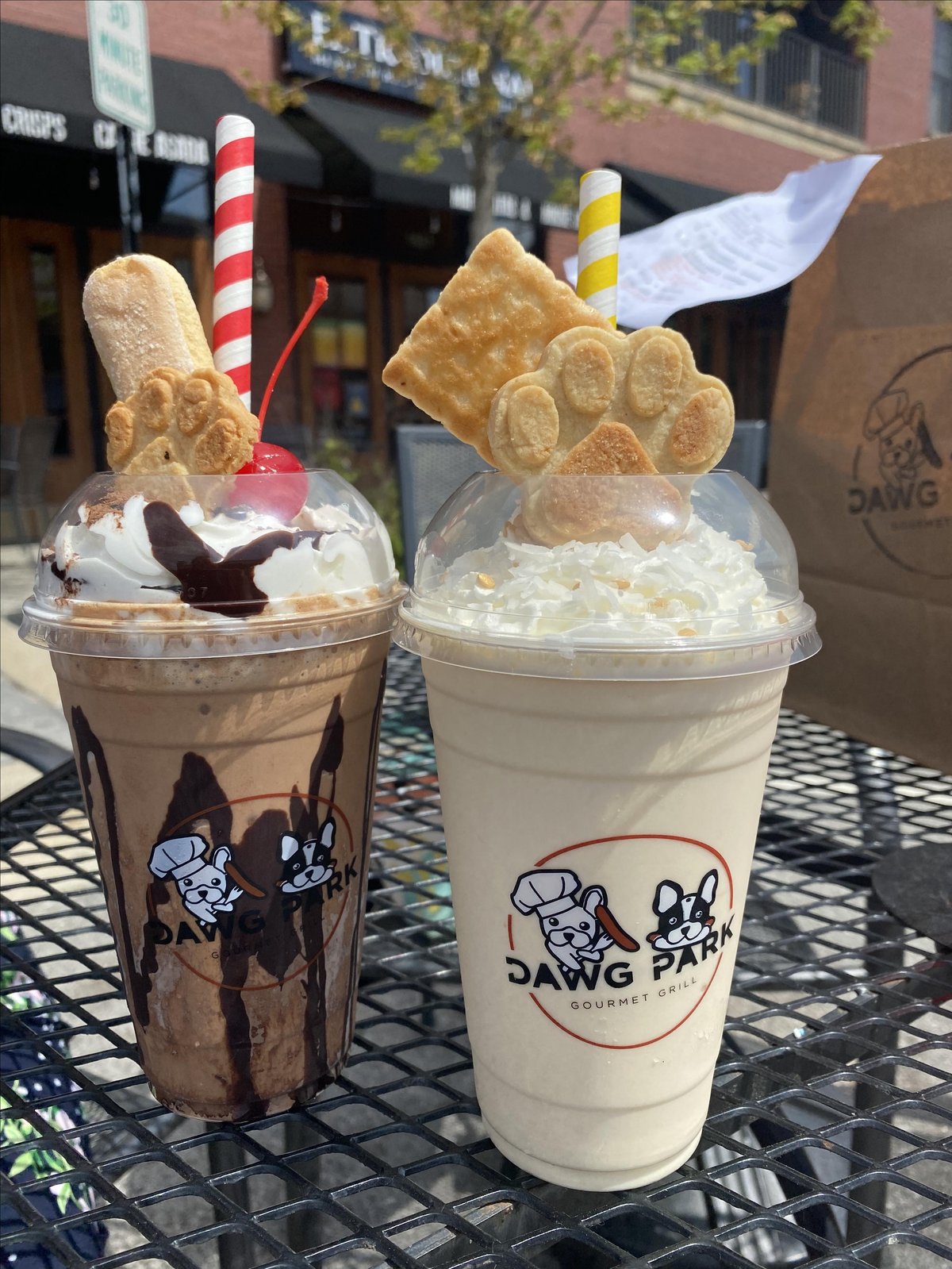 Two frozen drinks topped with whipped cream and a paw print cookie from DAWG PARK Gourmet Grill, a pet-friendly establishment in Glenview, IL.