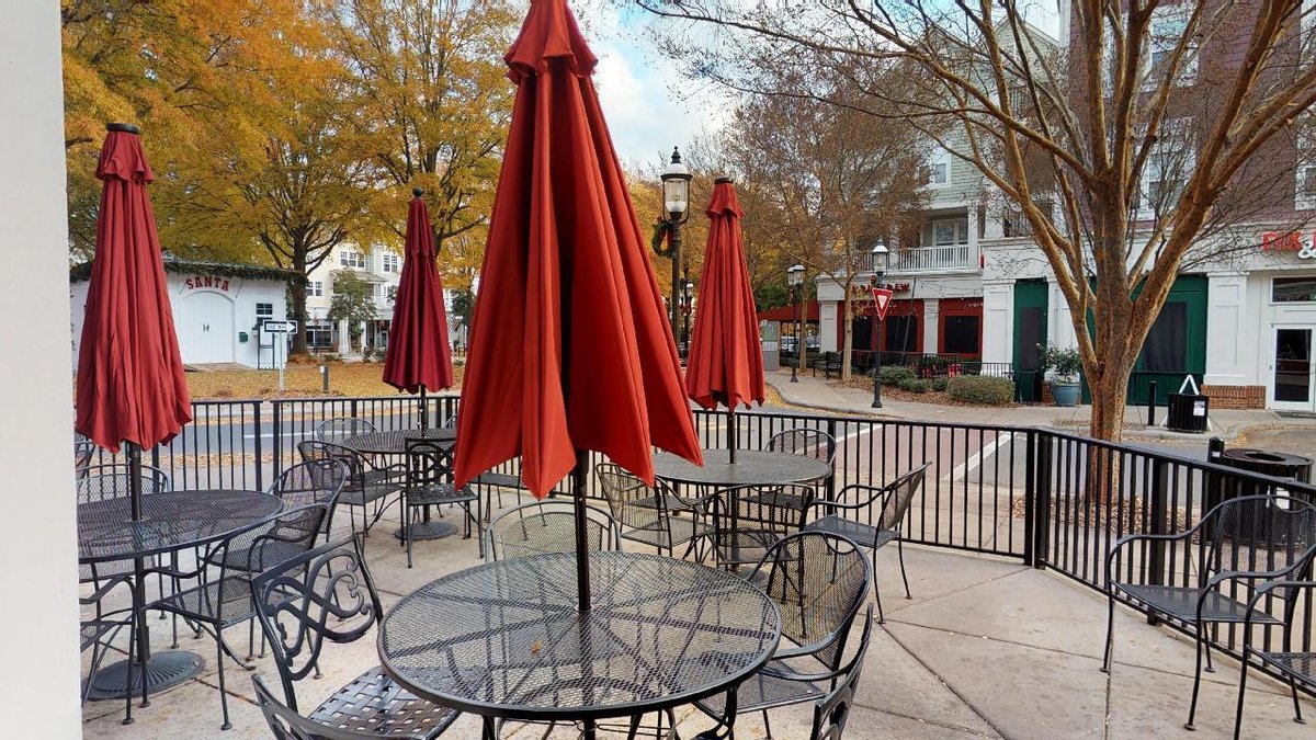 Umbrella-covered seating on the outdoor patio at pet-friendly Red Rocks Cafe-Birkdale Village in Huntersville, NC.