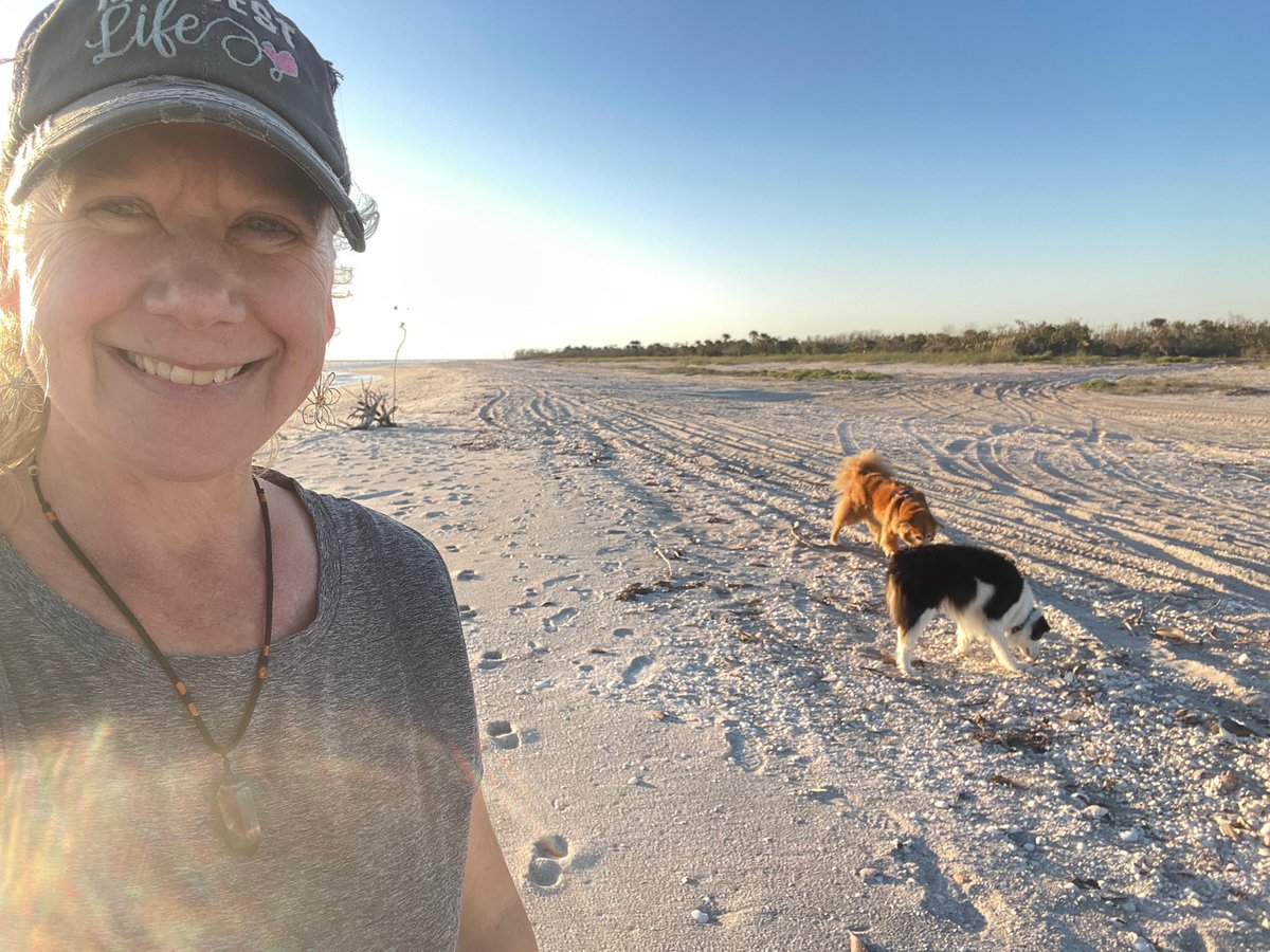 The dog-friendly owner of Serenity Sitters in Sanibel, FL, poses for a picture with dogs at the beach.